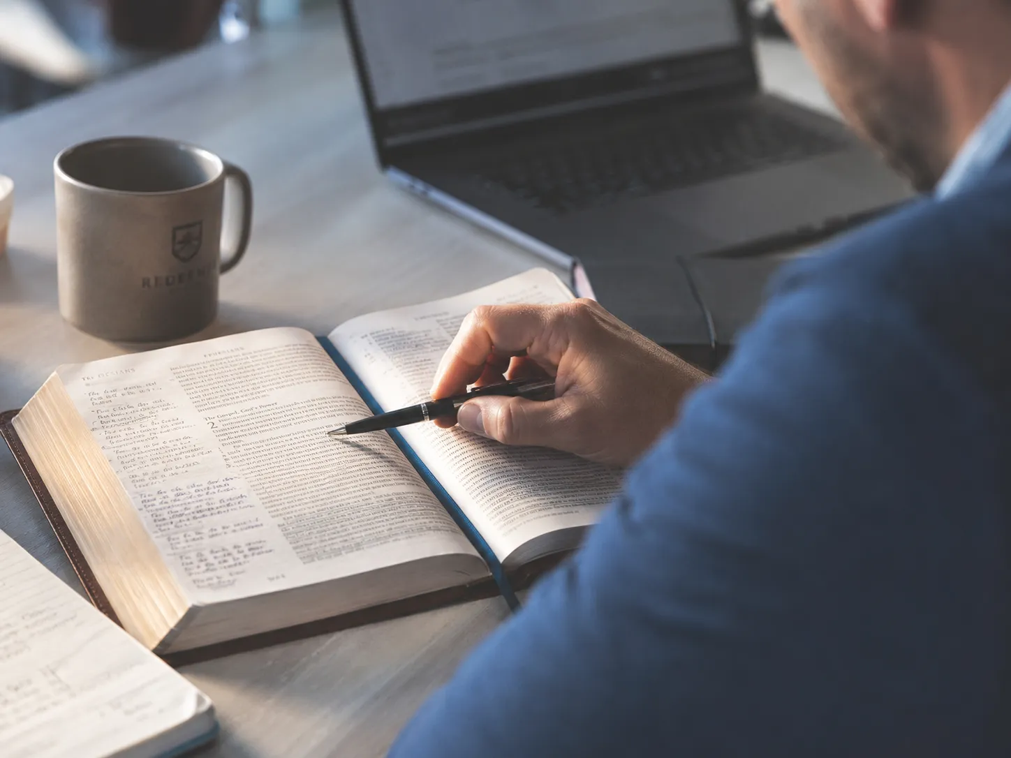 A minister studying an open Bible while writing notes